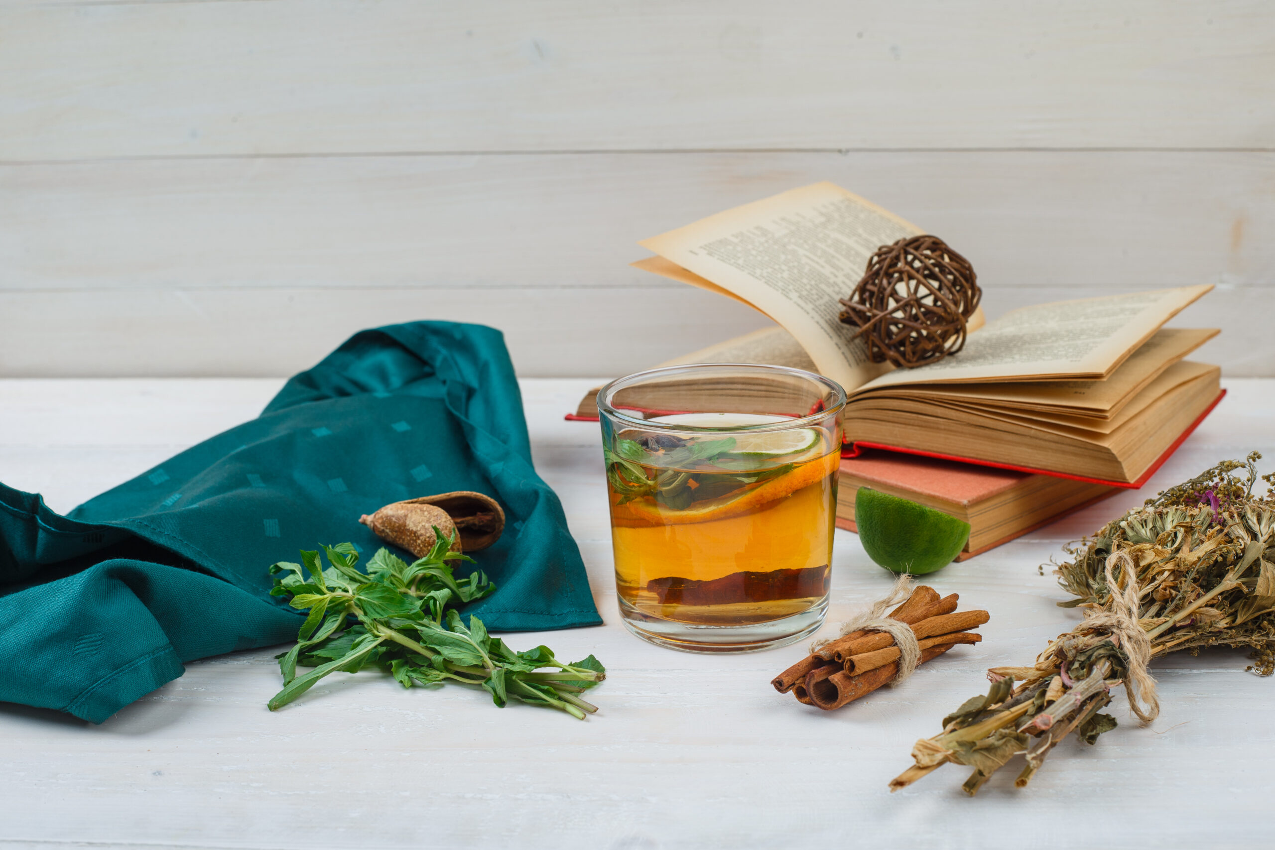 Close-up herbal tea and flowers with books,lemon, spices and green scarf on white background. horizontal